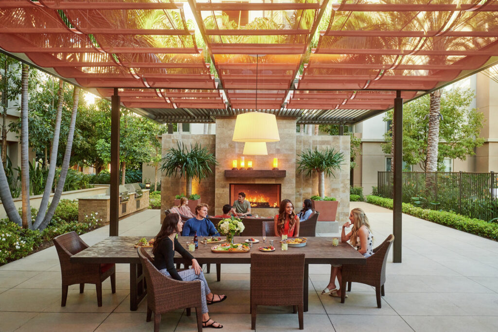 Friends sitting and socializing around an apartment's outdoor lounge table