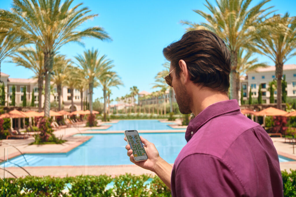 Man looking at TourGuide app in front of apartment pool